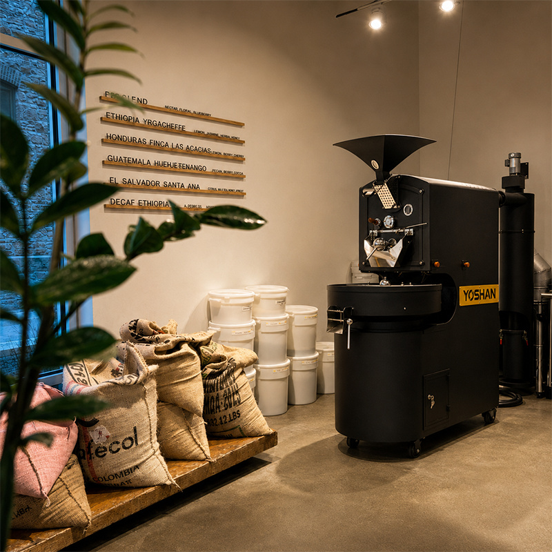 Yoshan coffee roaster in a roastery with bagged green coffee